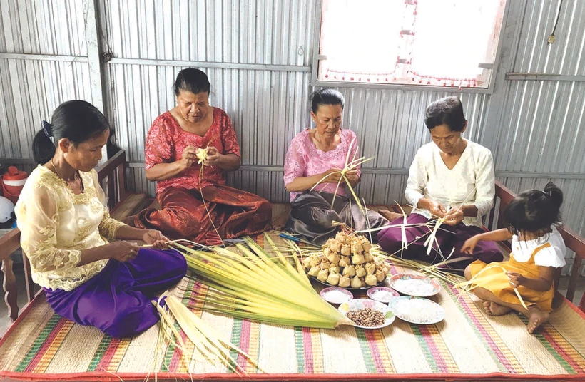 អ្នកស្រី នាង ភឿង (ទីពីរ ពីស្តាំទៅឆ្វេង) ណែនាំអ្នកម្តាយទាំងឡាយ បងៗ ស្រីនៅឃុំ អូឡឹម ស្រុក ទ្រីតូន (ខេត្ត អានយ៉ាង) ពីរបៀបវេចនំក៏ដូចជារបៀបលាយគ្រឿងផ្សំត្រៀមរៀបចំវេចនំ កាតំ